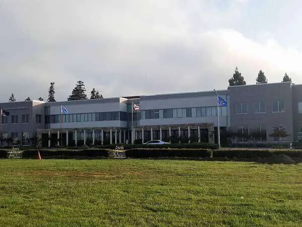 Large commercial building with stucco exterior and flags, Bay Area.